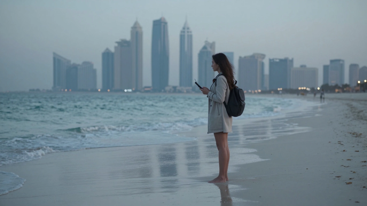 A woman standing alone on a Dubai beach at dawn, holding a burner phone.